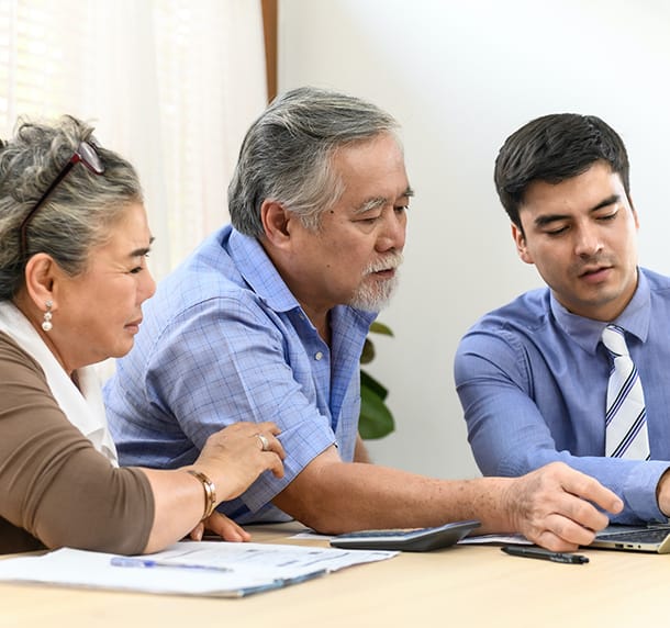 An estate planning attorney helps an elderly couple with trust & estate planning paperwork.